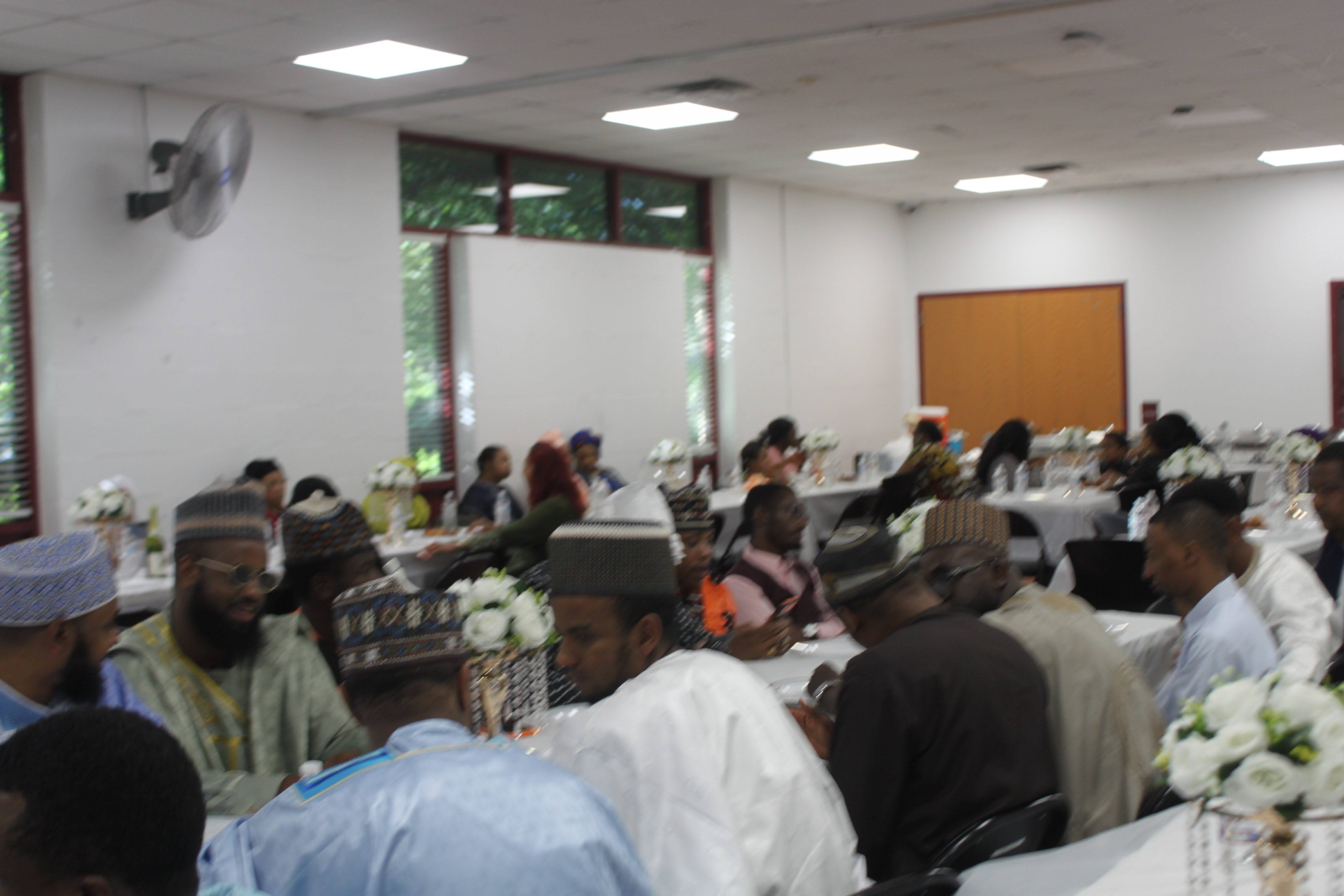A full hall of Fulani community members seated at decorated dinner tables during the Al Ada gathering