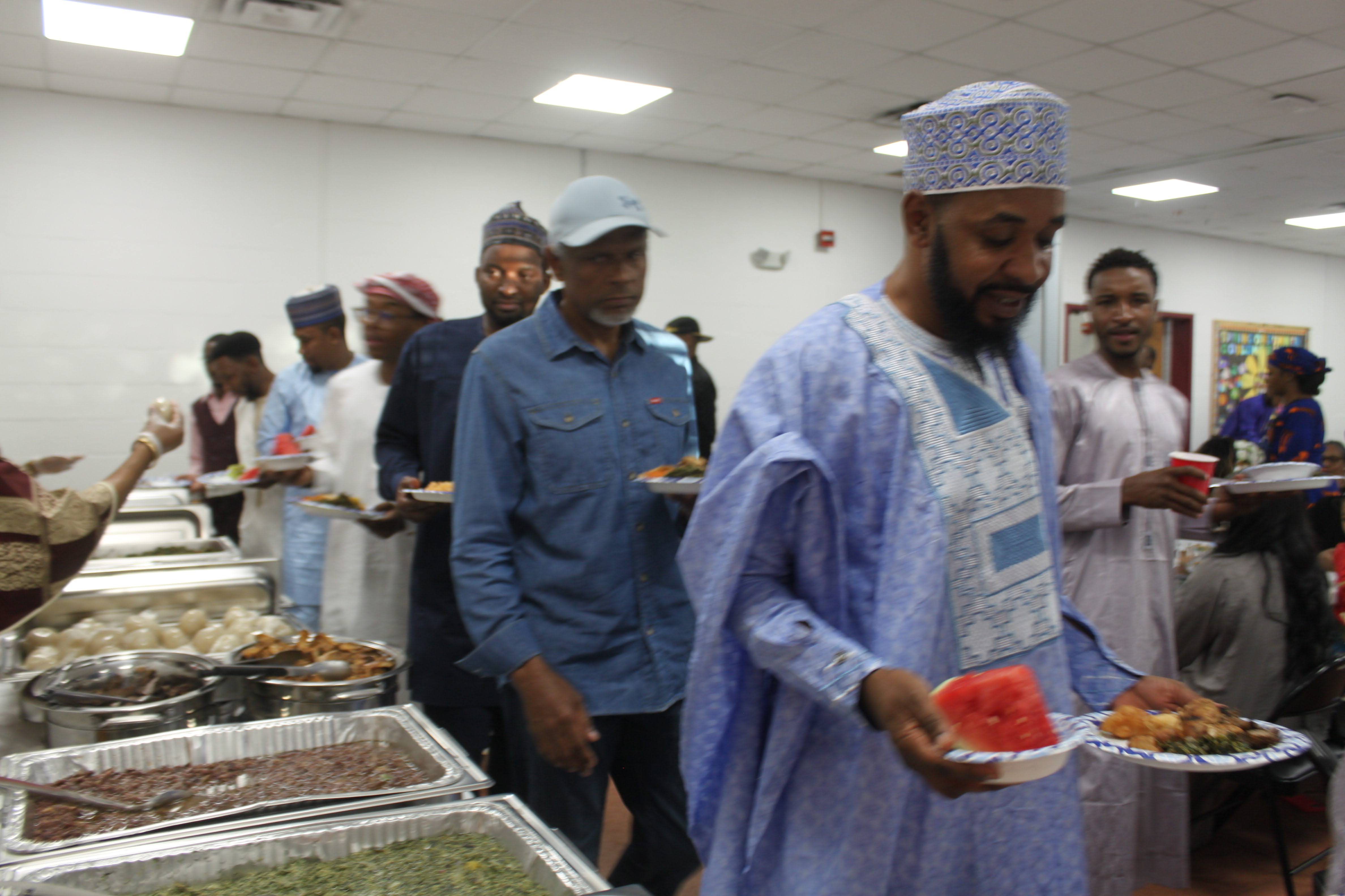 Youssoufa in a blue boubou and embroidered cap at the community dinner